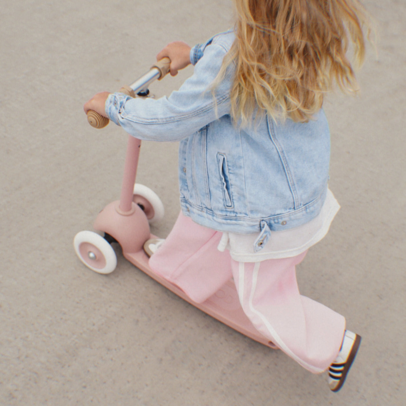 Toddler riding the Banwood Eco Scooter Dusty Rose